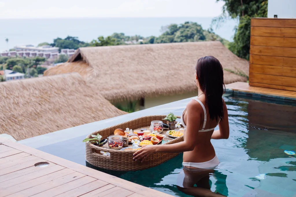 woman having tropical healthy breakfast villa floating table