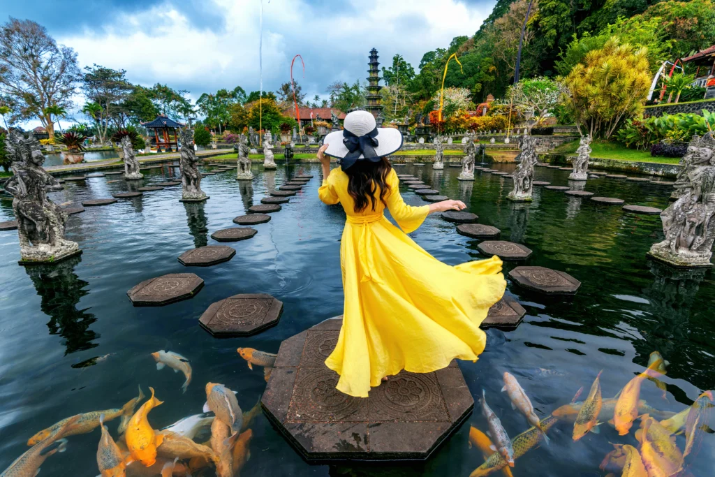 woman standing pond with colorful fish tirta gangga water palace bali indonesia